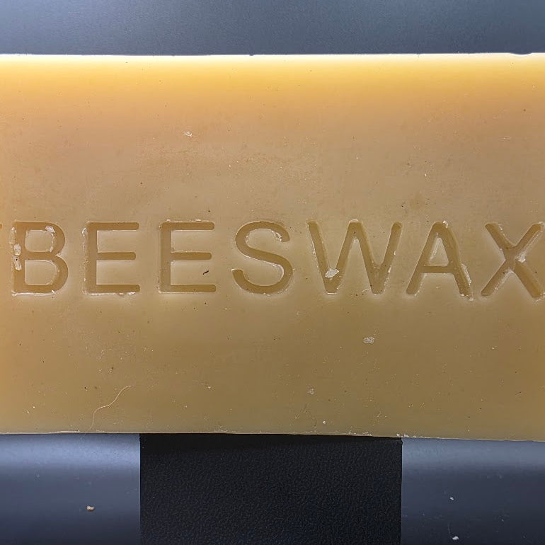 1 pound pure beeswax block on dark background