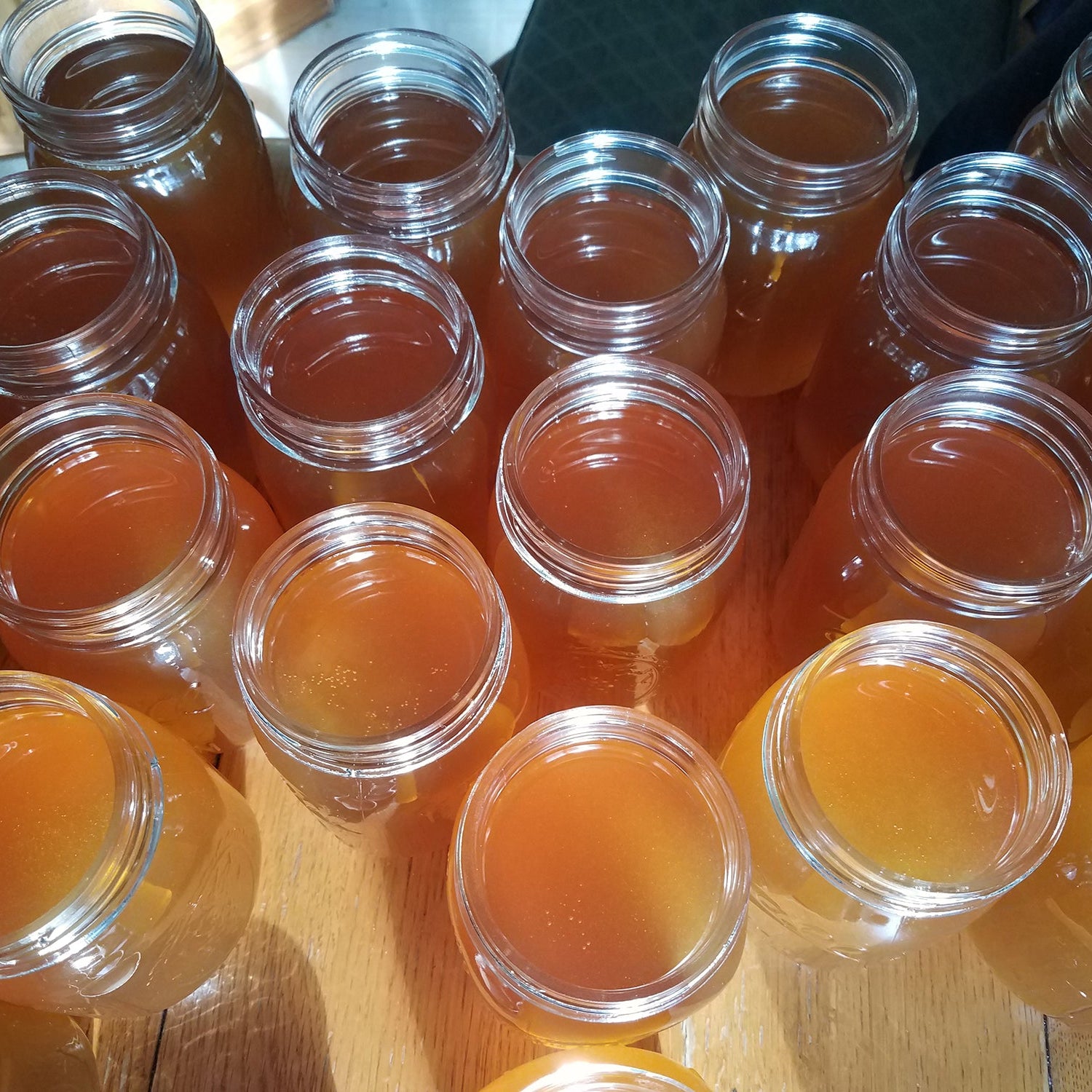 Multiple jars of multicolored honey on a wooden surface