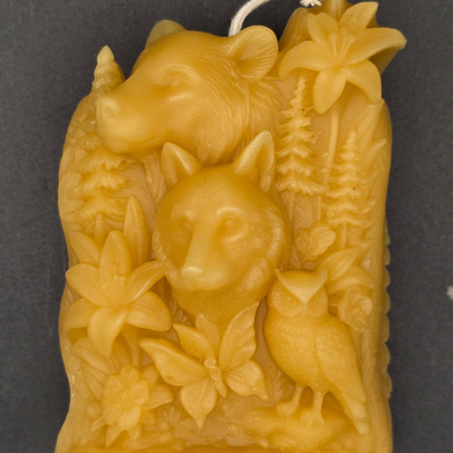 candle with animals bear wolf owl and floral design on a dark background