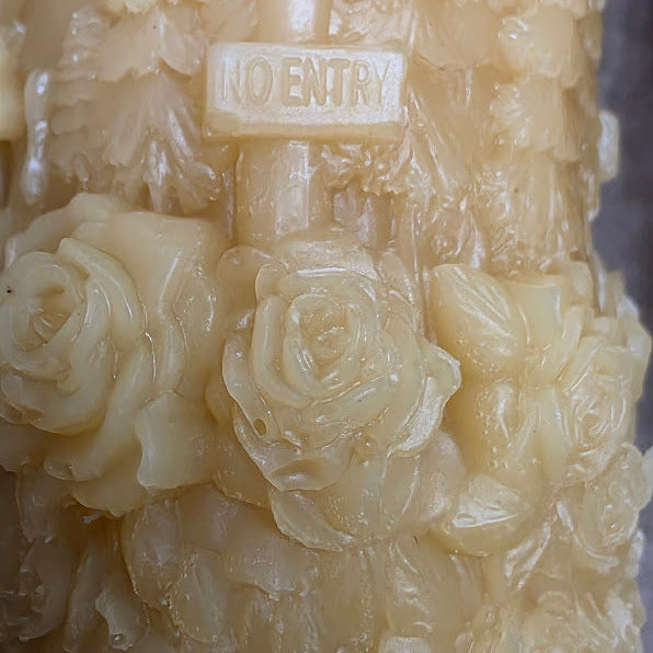 Decorative candle with floral patterns and 'No Entry' sign