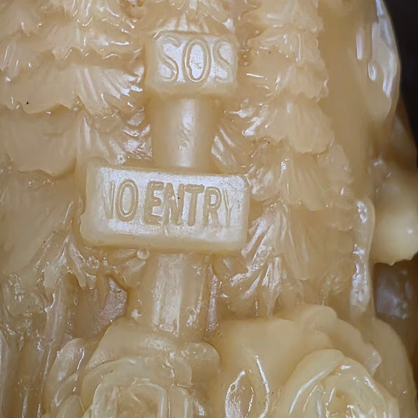 Close-up of candle with floral designs and 'SOS 10 ENTRY' text.