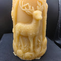 Beeswax candle with deer design on a dark surface