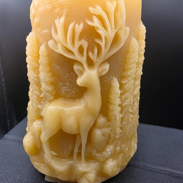 Beeswax candle with deer design on a dark surface