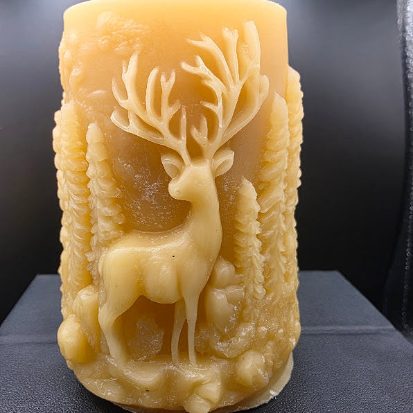 Beeswax candle with a deer design on a dark surface