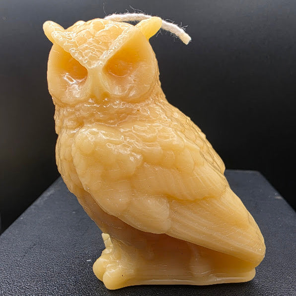 Owl-shaped candle on a dark surface
