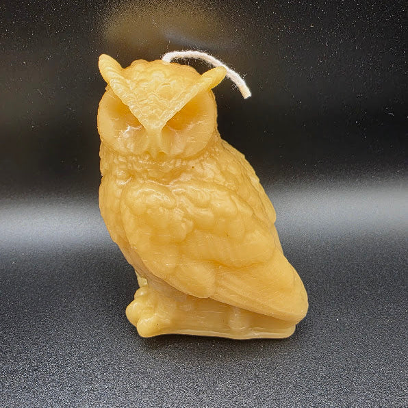 Beige owl-shaped candle on a black background