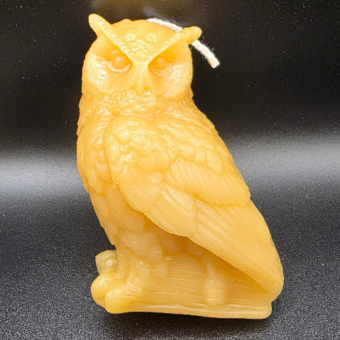 Beige owl-shaped candle on a black background