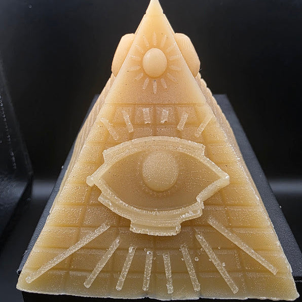 Triangular candle with eye design on a black background