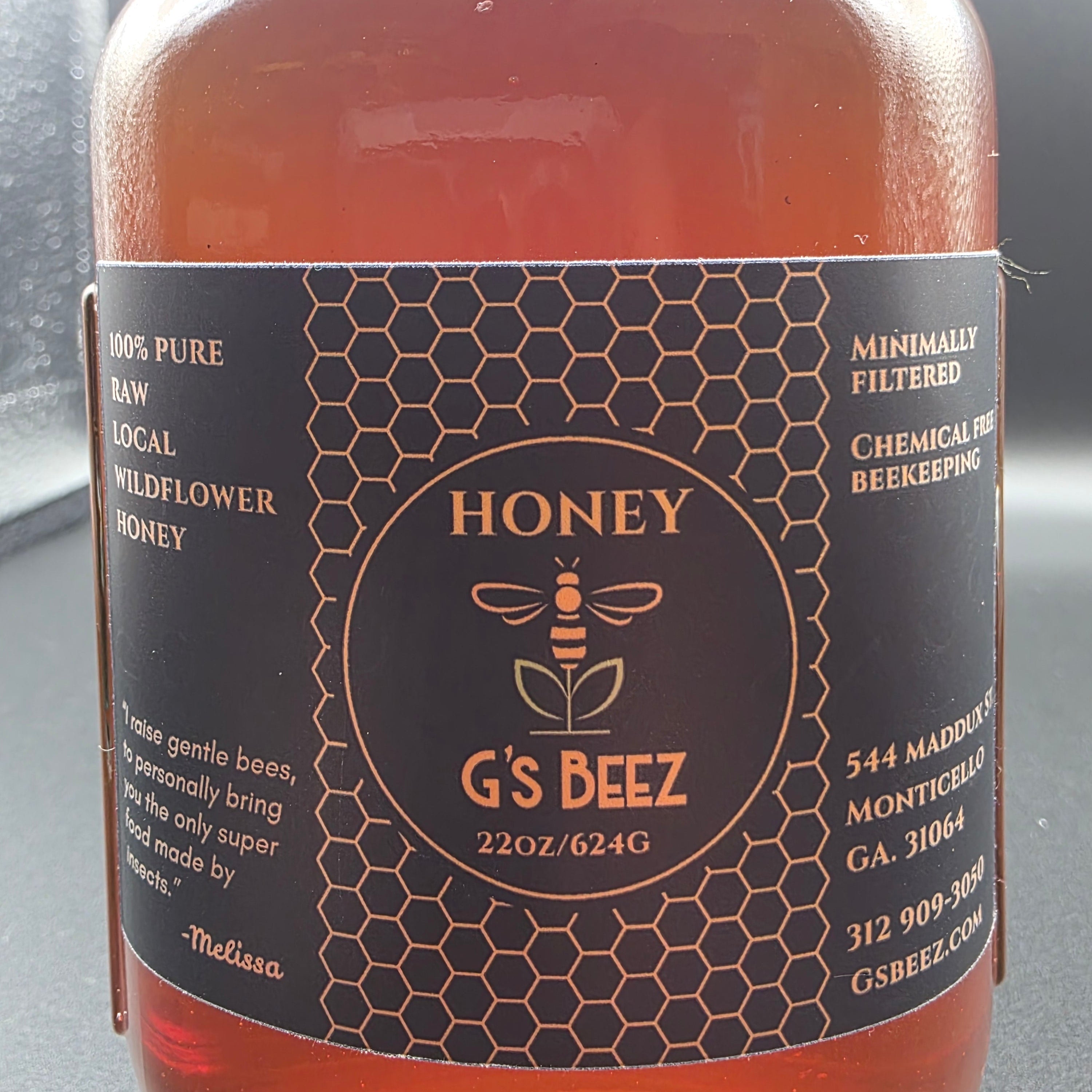 Bottle of honey with a label featuring the brand 'G's Beez' on a black background