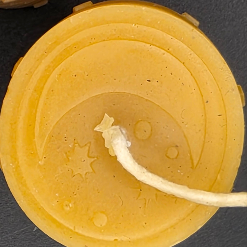 Close-up of a candle with star and moon designs on a dark background